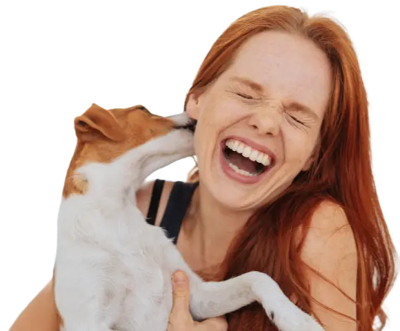 A smiling woman being licked by her dog